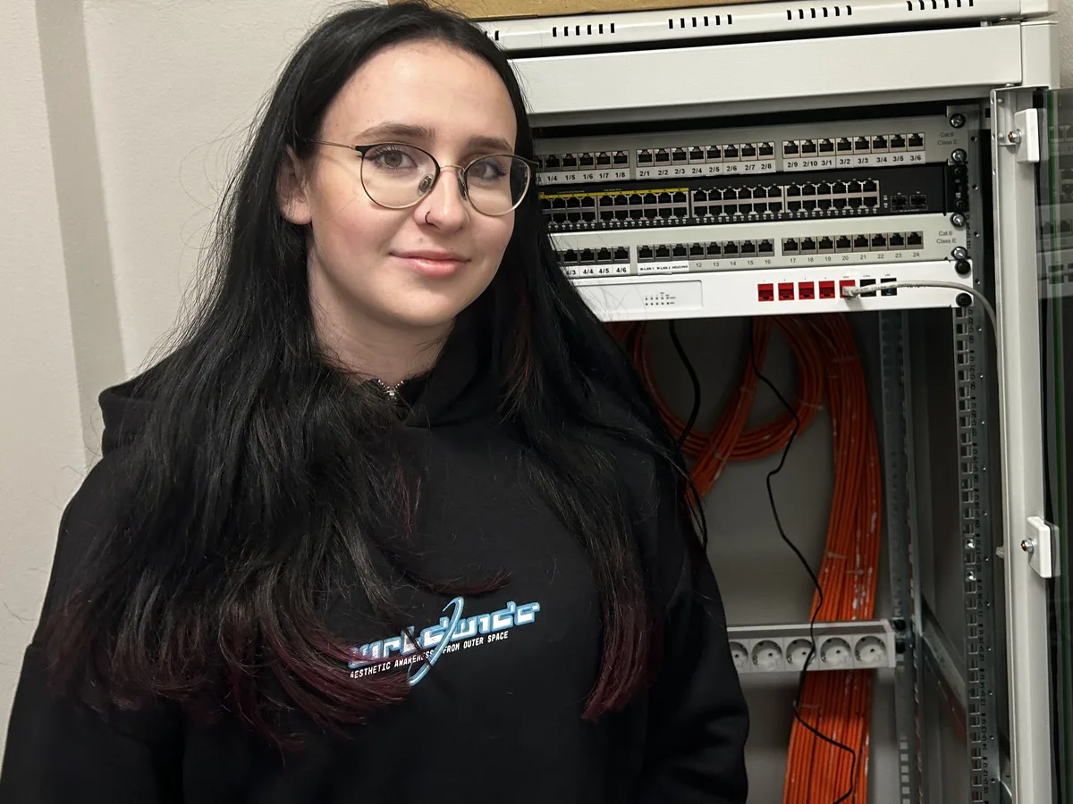 Miriam von andka-edv vor einem Netzwerkschrank mit Patchfeldern und Switch